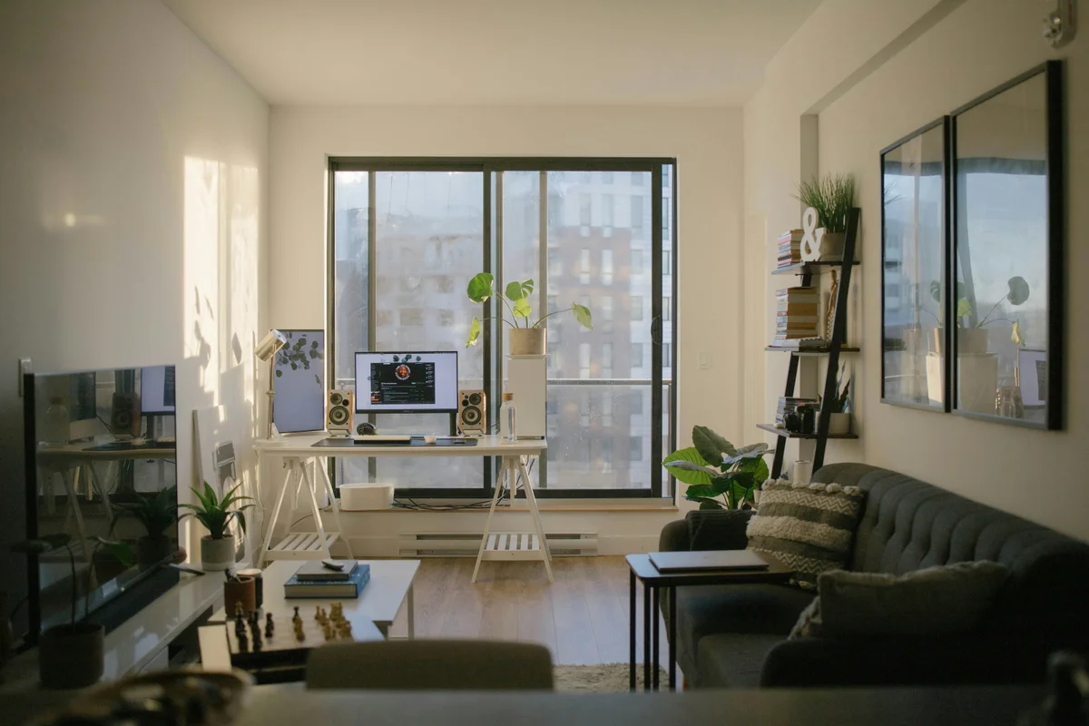 Sunlit apartment living room with desk setup, sofa, and city-view window