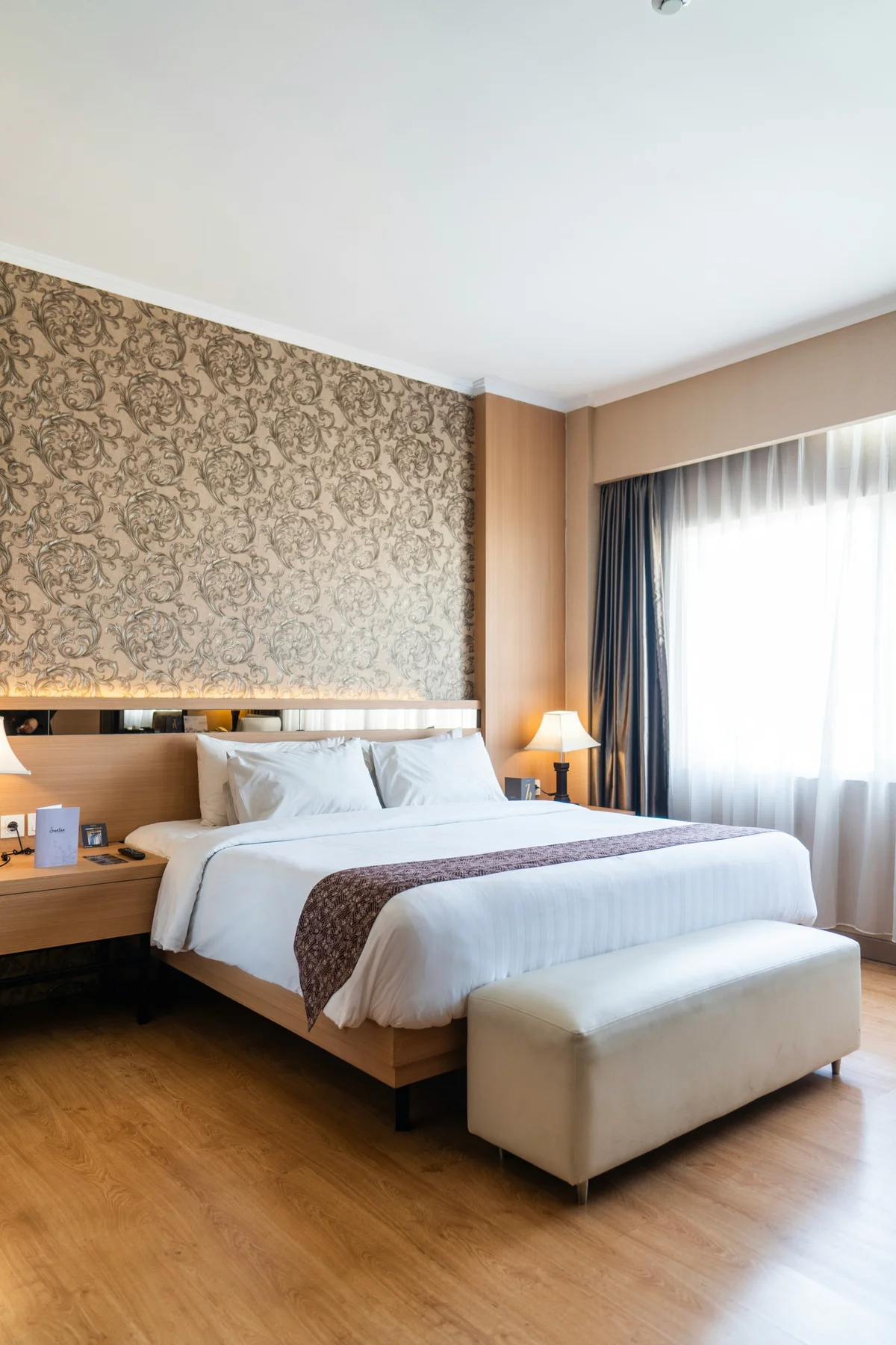 Hotel room with king bed, patterned accent wall, and bedside lamps
