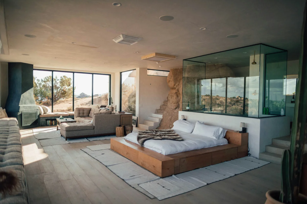 Open-plan desert retreat suite with platform bed and floor-to-ceiling windows