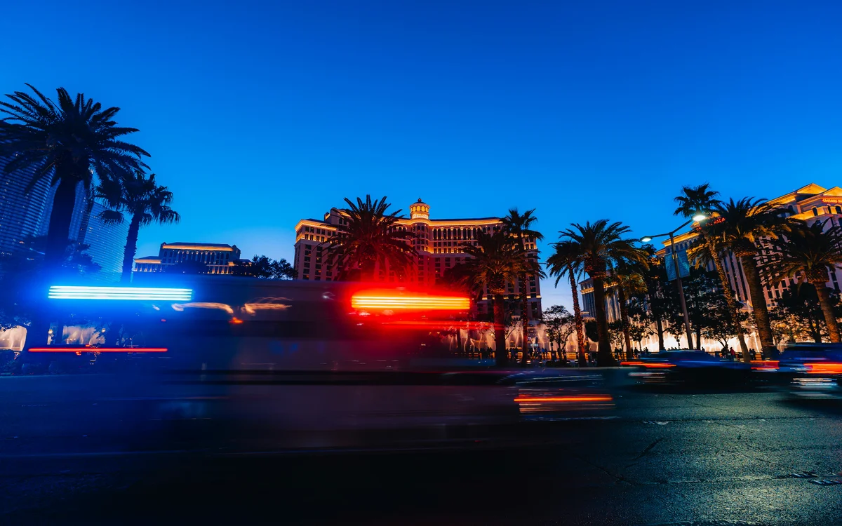 Hotel exterior at dusk with palm trees and motion-blurred vehicle lights