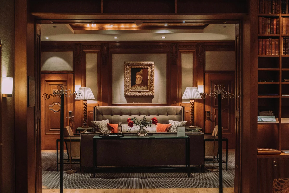 Upscale hotel library lounge with wood paneling, portrait painting, and accent pillows